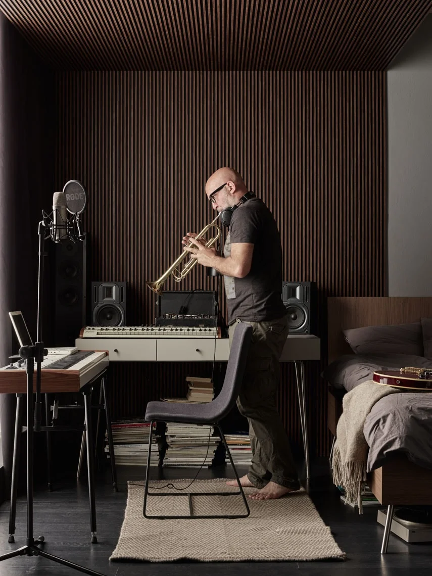  Mężczyzna gra na instrumencie, w tle panele ścienne